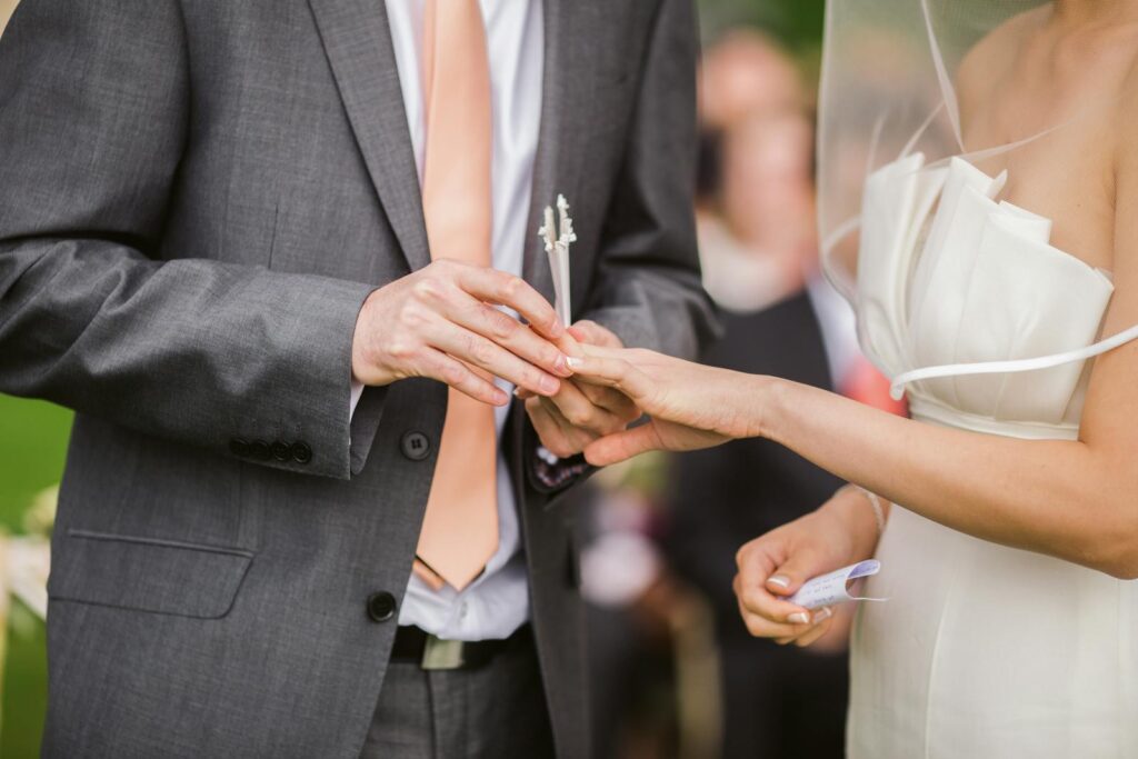 Close-up of a bride and groom exchanging rings during their wedding ceremony.