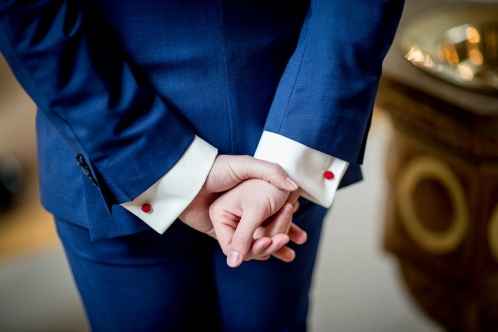 Close-up of an adult in a blue suit with hands crossed, showcasing elegance and business style.