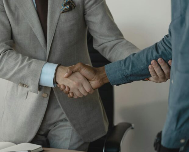 Image of a professional handshake between two businessmen in an office setting.